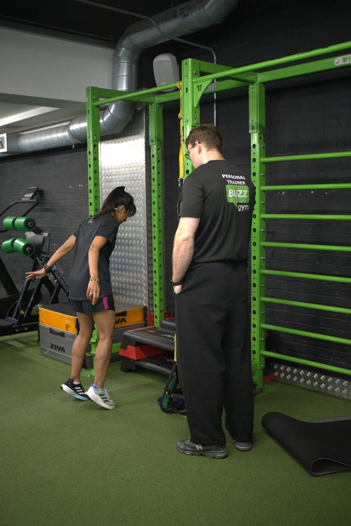 Manuel watching a client’s movement during a session in the functional training area at BuzzGym